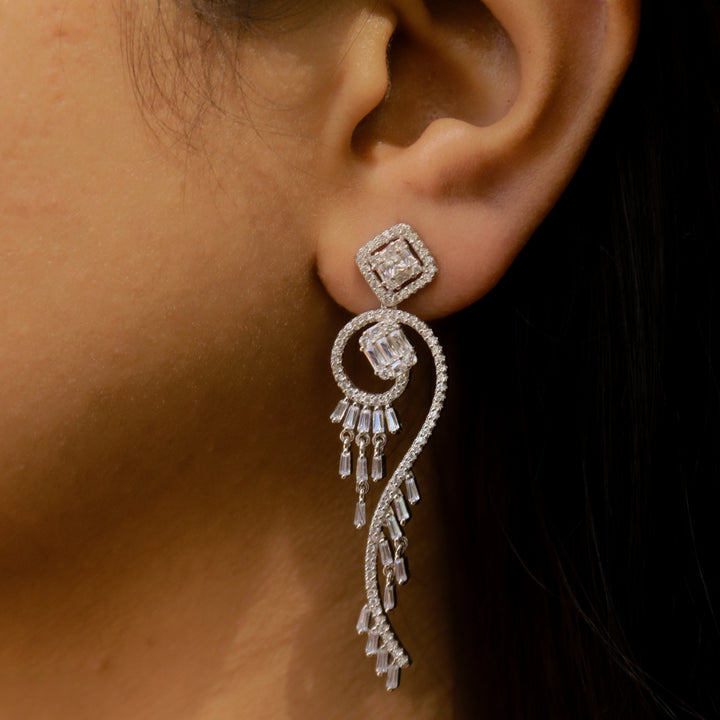 Close-up of an ear wearing a sparkling silver earring against a dark background